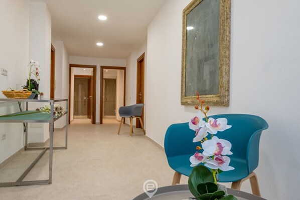 Un vestíbulo de hotel con una mesa de recepción, una silla azul y un cuadro colgado en la pared.