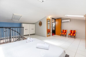 A hotel room with a bed, a staircase, a wardrobe, a mirror, and two chairs. - Charm in Via Abba - Cagliari (Cagliari)
