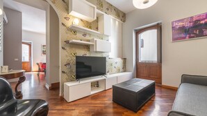 Un salon moderne doté d’un téléviseur à écran plat, d’étagères intégrées et d’un papier peint à motifs.