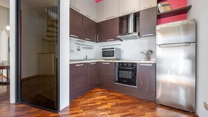 Une cuisine moderne avec des meubles de couleur sombre en bois, des appareils électroménagers en acier inoxydable et un parquet en bois disposé en motif chevron.