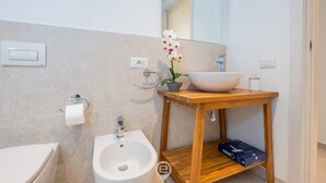 A modern bathroom with a white sink, bidet, and toilet. - Affittacamere Carmè - Suite Lido (Alghero)