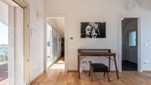 Une pièce spacieuse avec un plancher en bois, un banc noir et une œuvre d’art encadrée accrochée au mur.