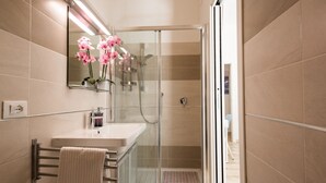 A modern bathroom with a glass shower enclosure, a white sink, and a mirror above it. - Coru e Mari - Suite Nora (Pula)