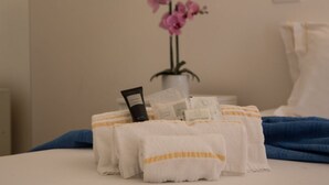 A neatly arranged hotel room with towels, toiletries, and a potted orchid plant. - Coru e Mari - Suite Nora (Pula)