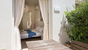 A bedroom with a bed, curtains, a bedside table, and a nightstand. There is a sign on the wall indicating the room number. - Coru e Mari - Suite Nora (Pula)
