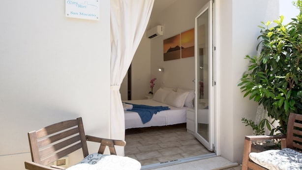 A bedroom with a bed, a nightstand, a chair, and a potted plant. - Coru e Mari - Suite San Macario (Pula)