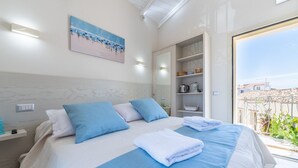 A modern hotel room with a large bed, a painting on the wall, and a view of the outside. - Il Ginepro - Suite Mare (Pula)