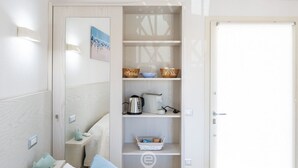 A compact, well-lit room with a built-in wardrobe, a small seating area, and a kitchenette. - Il Ginepro - Suite Mare (Pula)