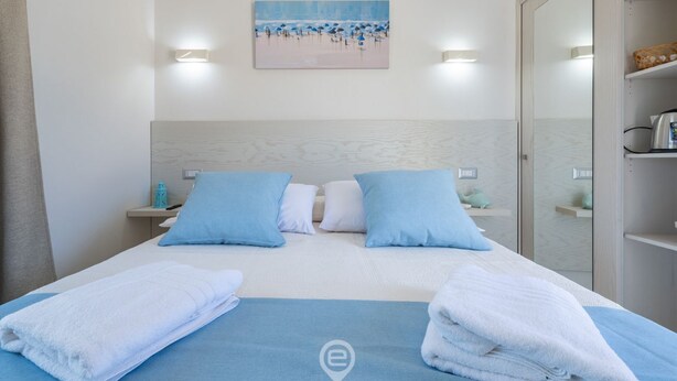 A hotel room with a bed, pillows, a painting, and a mirror. - Il Ginepro - Suite Mare (Pula)