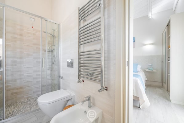 Ein modernes Badezimmer mit Duschkabine aus Glas, einer weißen Toilette und einem integrierten Waschbecken.