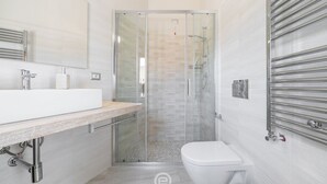 A modern bathroom with a glass-enclosed shower, a white sink, and a toilet. - Il Ginepro - Suite Mare (Pula)
