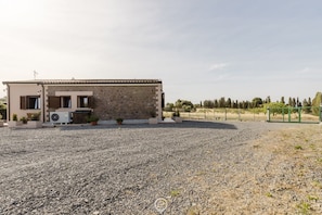 Un edificio con facciata in pietra, un portico coperto e un vialetto sterrato.