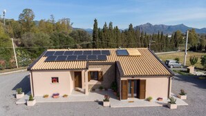 A two-story building with a tiled roof, solar panels, and potted plants. - House Adele - Camera 3 (Villa San Pietro)