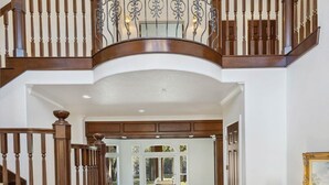 Un intérieur spacieux avec un escalier en bois menant à un balcon, une grande pièce ouverte offrant une vue dégagée et une petite table avec une lampe.