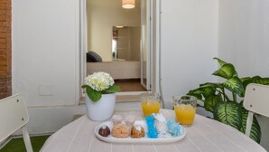Un tavolino con un vassoio di biscotti e due bicchieri di succo d'arancia, una pianta in vaso e una sedia.