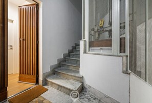 A staircase leading to a door with a wooden panel design. - AcquaChiara Suite - Elegance and Comfort in the Heart of Cagliari (Cagliari)
