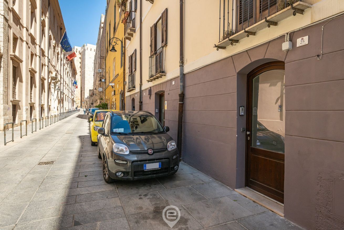 Una calle estrecha con coches aparcados y edificios a ambos lados.