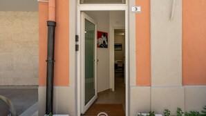 A hotel entrance with a glass door, a number '3' sign, and a small hallway leading inside. - Saturnino - Apartment (Cagliari)