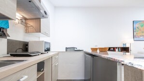 A compact kitchen with a microwave, toaster, and a small island with a sink. - Saturnino - Apartment (Cagliari)