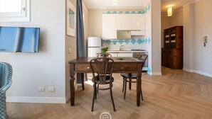 Un coin repas avec une table et des chaises en bois, une cuisine à l’arrière-plan et un meuble en bois.