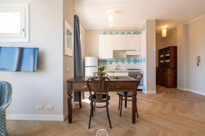 Un coin repas avec une table et des chaises en bois, une cuisine à l’arrière-plan et un meuble en bois.