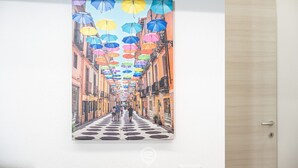 Un tableau représentant une rue bordée de parasols colorés et de bâtiments.