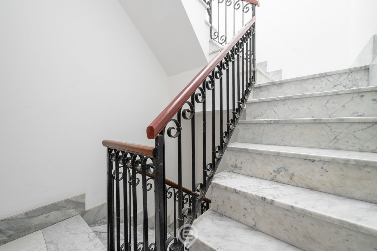 Un escalier avec des marches en marbre et des rampes en métal noir.