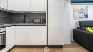 Une cuisine moderne avec des meubles blancs, un four à micro-ondes et un four encastré.