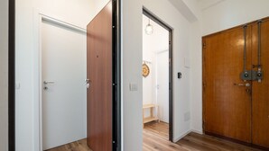 Ein Korridor mit Holzboden und weißen Türen, der in einen Raum mit einem Holzschrank und einer Pendelleuchte führt.