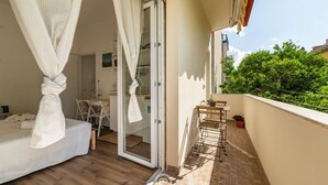Ein Balkon mit einem Bett, einem Tisch und Stühlen.