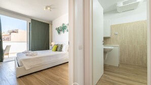 Una camera d'albergo moderna con un letto, un bagno piccolo e vista sulla città.