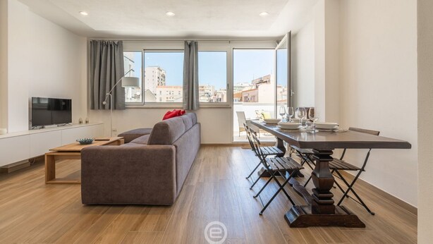 Un appartamento moderno con zona giorno, sala da pranzo e ampie finestre con vista sulla città.