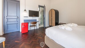 Ein Hotelzimmer mit einem Bett, einem Schreibtisch mit Computer, einem roten Kühlschrank, einem Stuhl und einem Kleiderschrank.