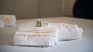 Ein ordentlich gefaltetes weißes Handtuch mit orangenen Streifen auf einem Bett.
