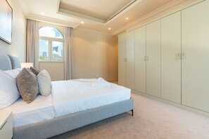 Een slaapkamer met een bed, een kast en een raam met uitzicht op gebouwen.