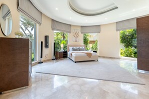 Un dormitorio amplio con una cama grande, un televisor de pantalla plana y vistas a zonas verdes.