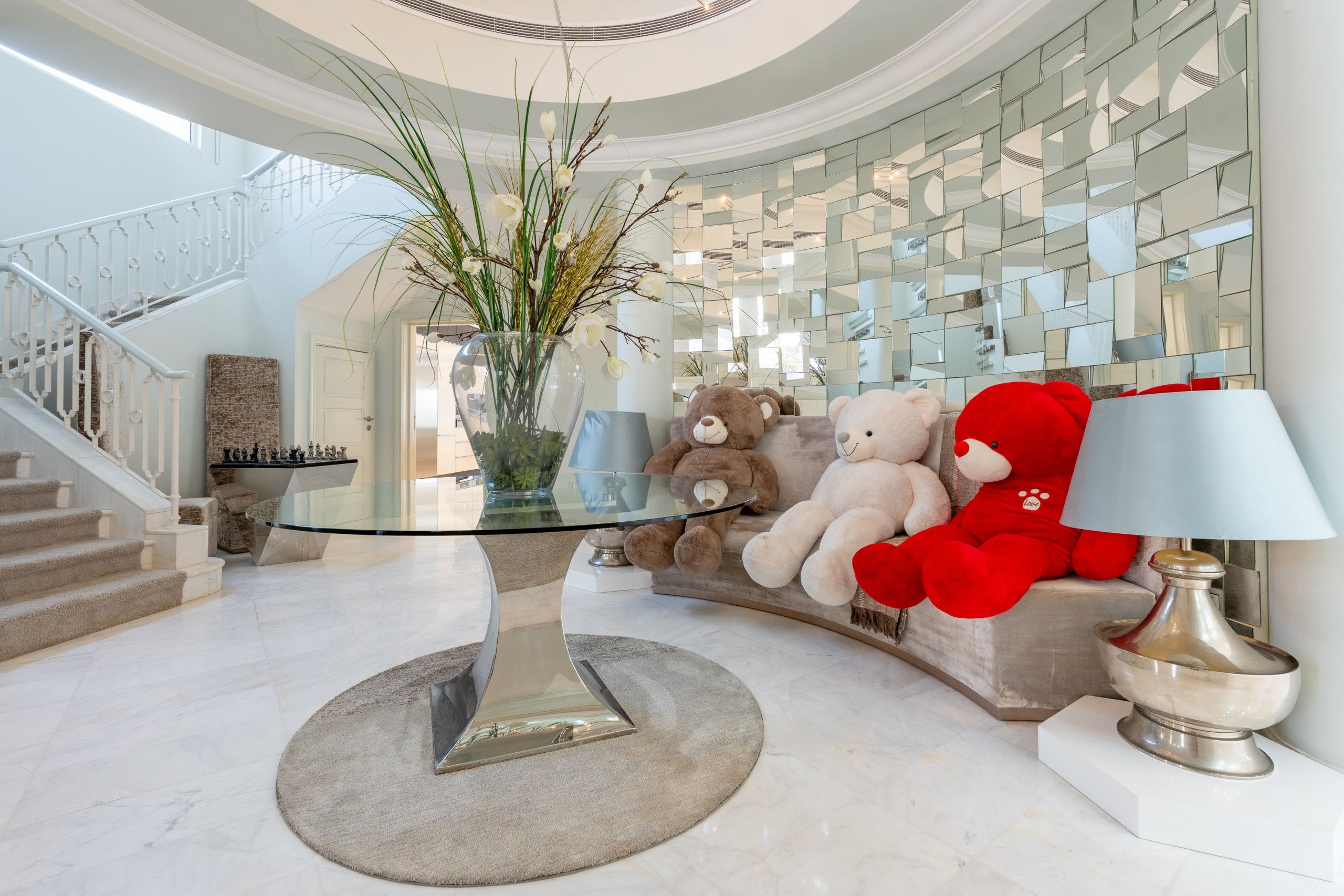 A modern interior with a glass coffee table, plush sofas, and a decorative vase with plants.