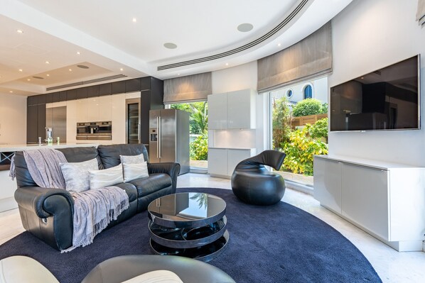 Un salon moderne avec un canapé en cuir noir, une table basse en verre et un fauteuil en forme de poire noir.