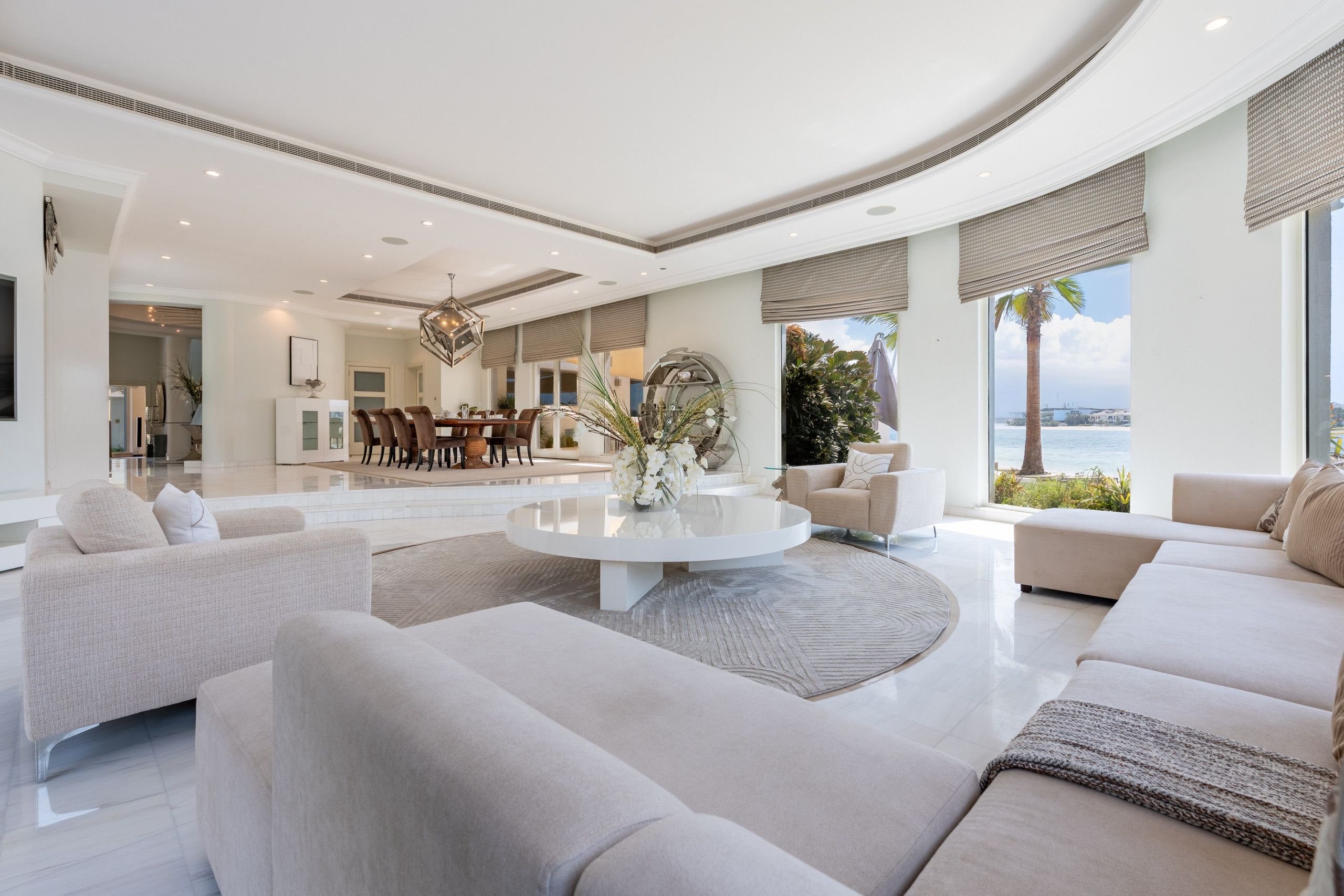 Un vaste espace de vie comprenant une table basse ronde, des canapés et une vue sur la mer.