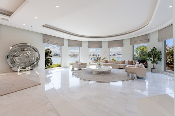 A spacious living area with a central coffee table, sofas, and a decorative metal sculpture.