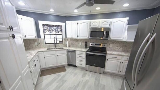 A modern kitchen with white cabinets, stainless steel appliances, and a marble countertop.