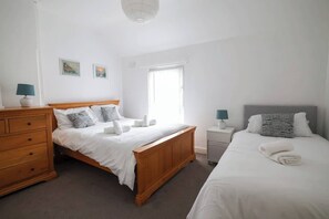 A bedroom with a wooden bed, a nightstand, a dresser, and a window with curtains. - City Centre House Near Attractions & Free Parking (Belfast)