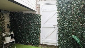 Une porte de garage blanche, un mur blanc et une haie.