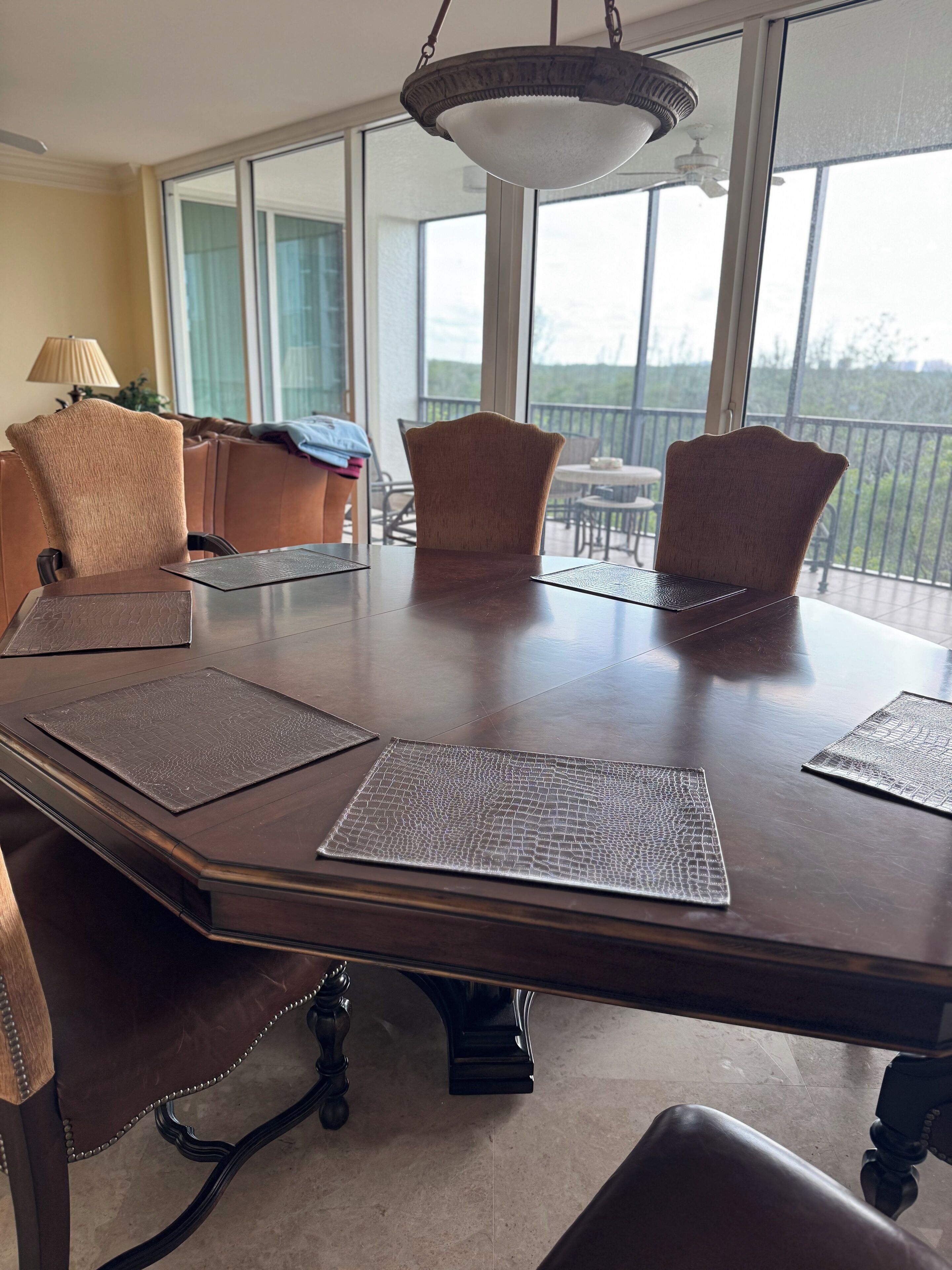 Un espace repas comprenant une grande table, des chaises et une vue sur l’extérieur grâce à de grandes fenêtres.