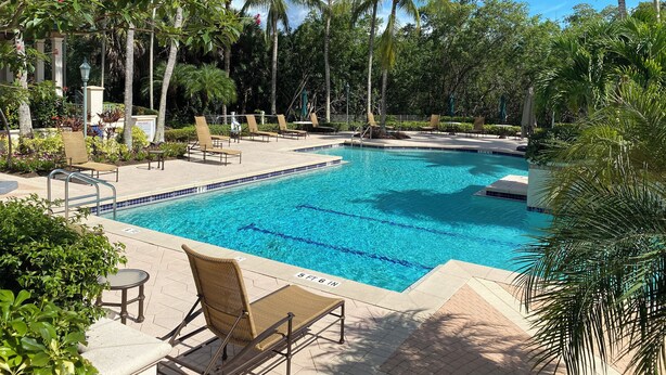 Uma área de piscina com espreguiçadeiras e palmeiras.