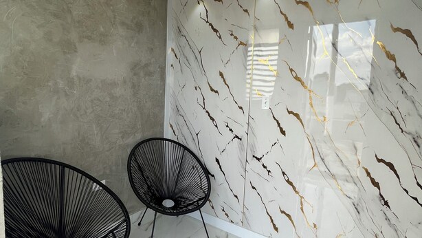 A modern interior with a marble-patterned wall, two black wire chairs, and a tiled floor. - Molinos House 1 (Santa Isabel)