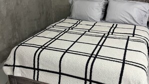 A bed with a plaid bedspread, wooden headboard, and white pillows. - Molinos House 1 (Santa Isabel)