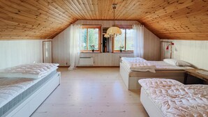 Ein Zimmer mit zwei Betten, Holzboden, großen Fenstern und einer Hängelampe.