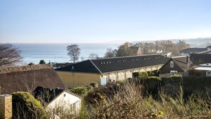 Un quartier résidentiel situé sur la côte, avec des maisons, un bâtiment à toit de chaume et une vue sur la mer.