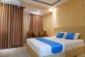 Quarto de hotel com uma cama grande, cabeceira de madeira e ar condicionado instalado no teto.